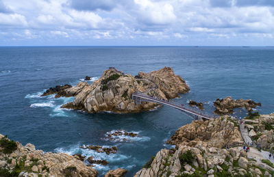 Rocks on shore by sea against sky