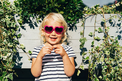 Little happy laughing blonde girl in sunglasses looks at the camera. 