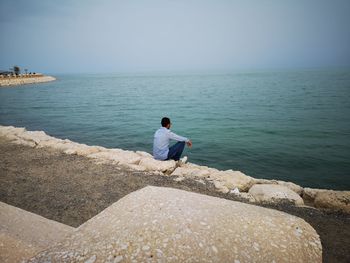 Rear view of man looking at sea against sky