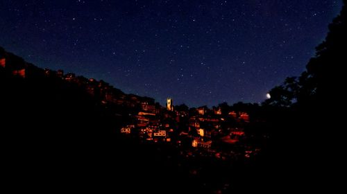 Illuminated buildings in city against clear sky at night