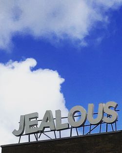 Low angle view of sign board against cloudy sky