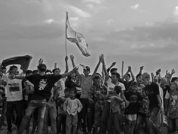 Happy fans standing against sky