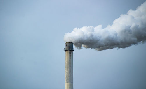 Smoke emitting from chimney against sky