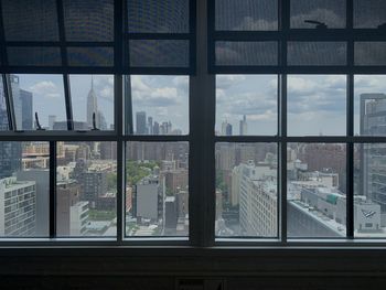 New york city skyline buildings and empire state building seen through glass window with blinds