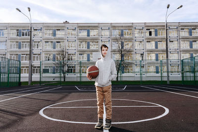 Full length of boy standing on basketball field