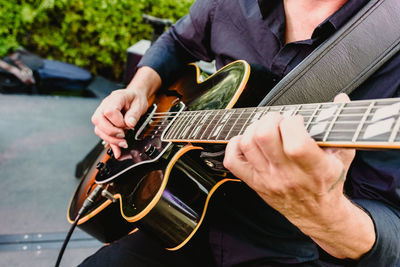 Midsection of man playing guitar