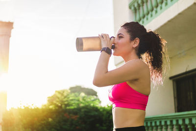 Young athlete taking a break and drinking something to cool off