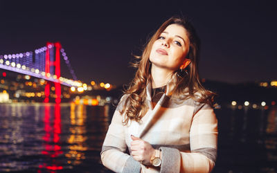 Portrait of woman standing in illuminated city at night