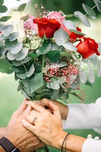 Close-up of couple holding bouquet of red roses