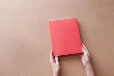 Close-up of hand holding book against white background