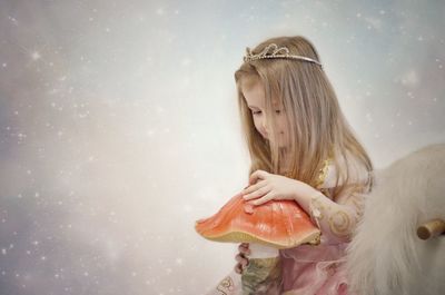 Digital composite image of girl wearing princess costume with artificial mushroom against glittering backgrounds