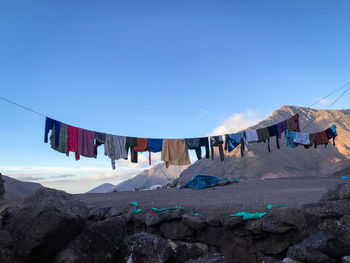 Low angle view of clothes drying against clear blue sky with snowy mountains in the background 