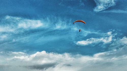 Low angle view of person paragliding against sky