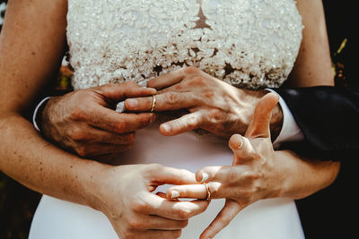 Midsection of couple embracing during wedding ceremony