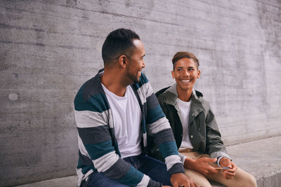 Young couple sitting against wall