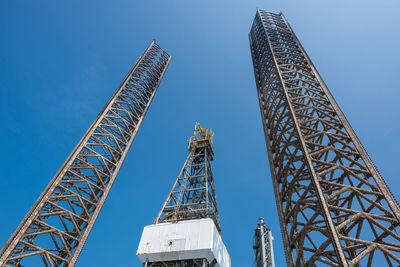 Low angle view of crane against clear blue sky