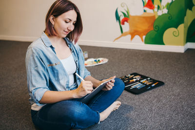 Woman using digital tablet while sitting at home