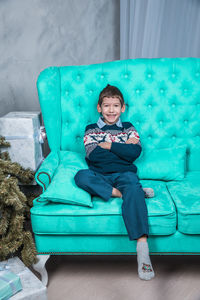 Portrait of smiling boy sitting on sofa at home