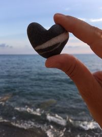 Midsection of person holding heart shape on beach