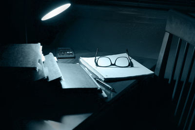 Illuminated lamp with files and eyeglasses on table