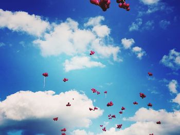 Low angle view of balloons flying in cloudy sky