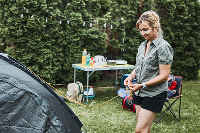 Woman putting up a tent at camping during summer vacation. preparing campsite to rest and relax