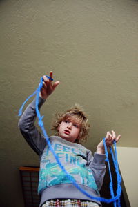 Low angle view of boy playing with blue rope against ceiling