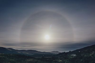 Scenic view of sea against sundog during sunset