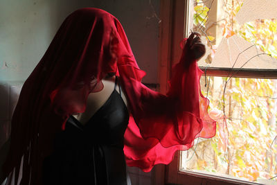 Woman with red scarf standing by window