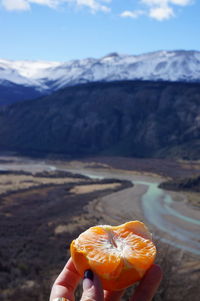 Person holding ice cream against mountains