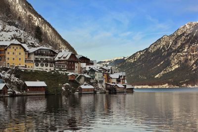 Residential district by lake and mountains against cloudy sky