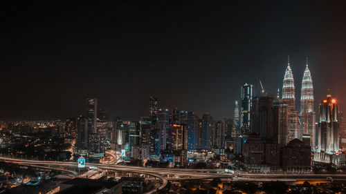 Illuminated buildings in city against sky at night