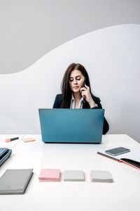 Young woman using phone while sitting on table