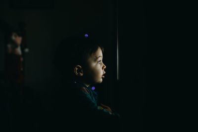 Side view of boy looking away in darkroom