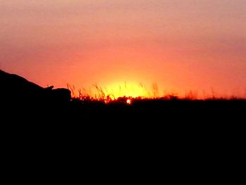 Silhouette landscape against dramatic sky during sunset