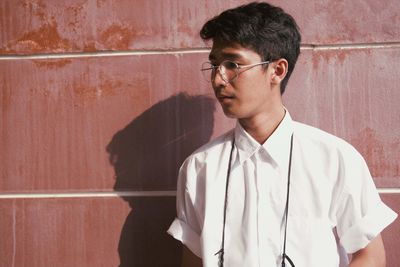 Portrait of young man standing against wall