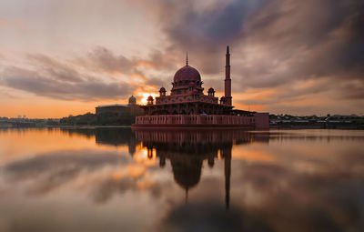 Reflection of putra mosque on calm lake against sky during sunset