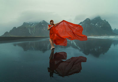 Graceful woman wrapped with red chiffon on beach scenic photography