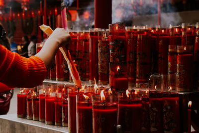 Midsection of person holding candles in temple