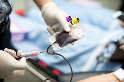 Cropped hand of doctor injecting in blood bag
