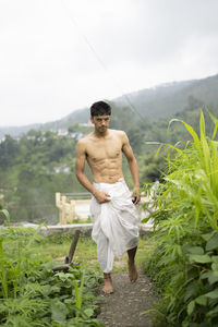 Young indian fit boy, walking on a pathway beside crops in the field. an indian priest walking .