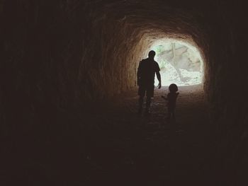 Silhouette father with daughter standing in cave