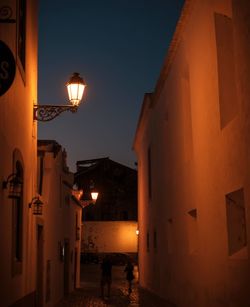 Illuminated street amidst buildings at night