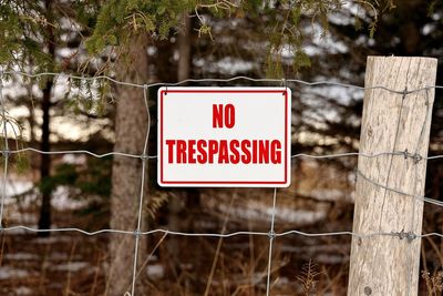 No trespassing sign posted on a wire fence in a rural setting. high quality photo