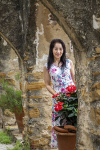 Portrait of a smiling young woman standing against plants