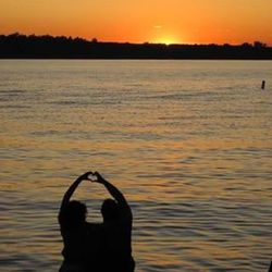 Silhouette of people in lake at sunset