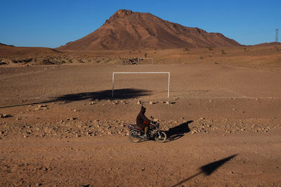 Person with umbrella on desert against sky