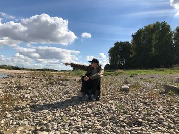 Young man pointing while sitting at beach