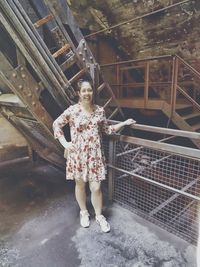 Portrait of woman standing against railing