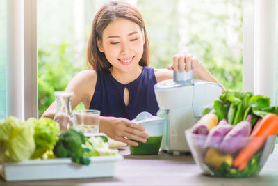 Young woman making juice at table